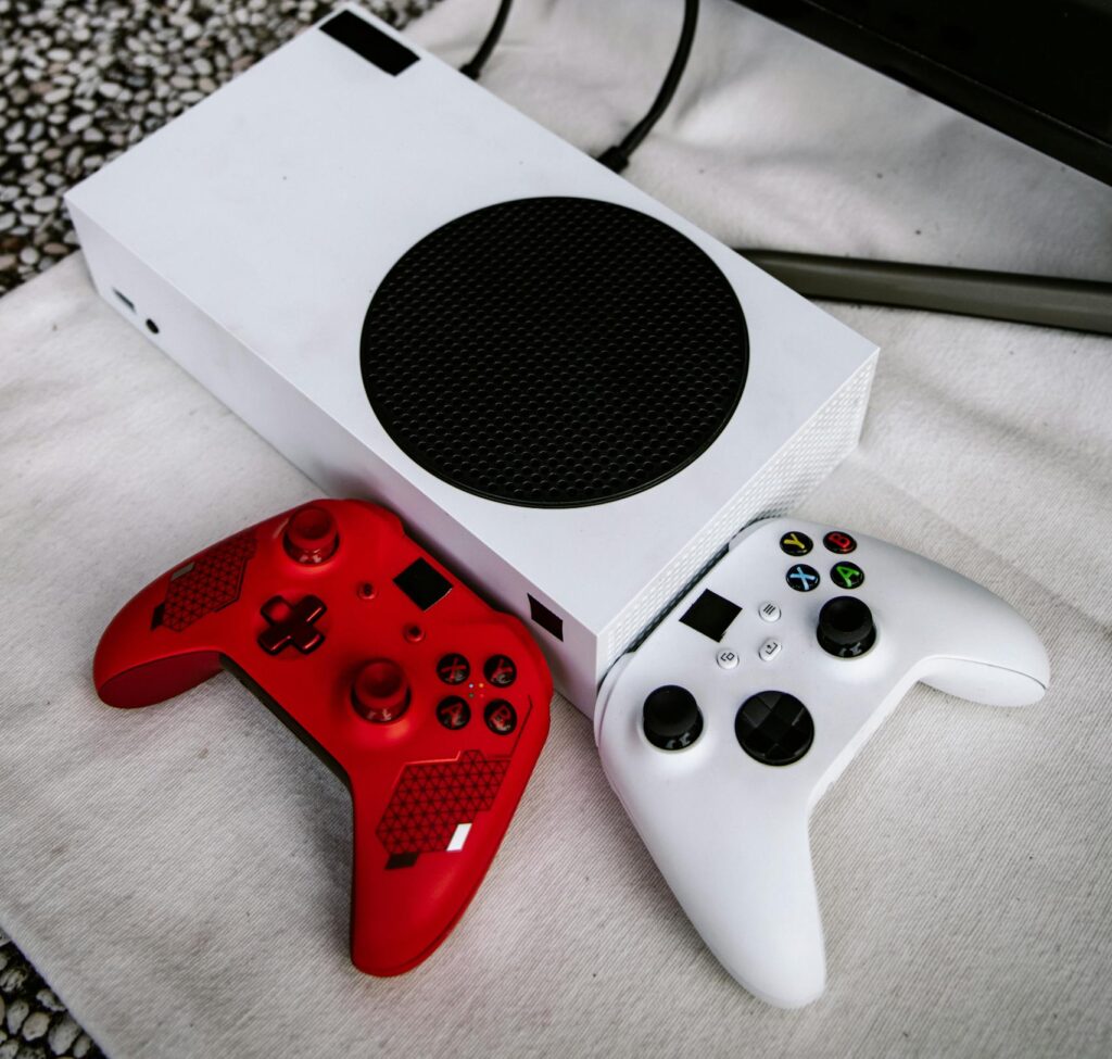 Red and white Xbox controllers with a console in a modern gaming setup.